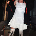 Ryder in a white dress and black fluffy coat taking a flash photo in a dark porch area